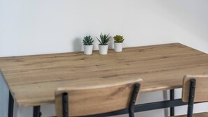 Ein Holztisch mit drei Blumentöpfen und zwei Stühlen.