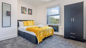 Ein Schlafzimmer mit einem Bett, einem Kleiderschrank, einem Fenster mit Ausblick und zwei Bildern an der Wand.