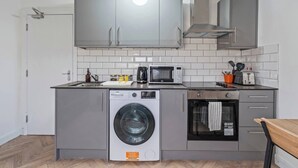 Eine kleine Küche mit Waschmaschine, Mikrowelle und kleinem Backofen.