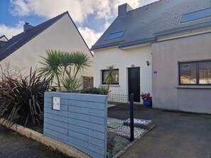 Ein Wohngebäude mit geneigtem Dach, einer sichtbaren Tür und einem kleinen Fenster.