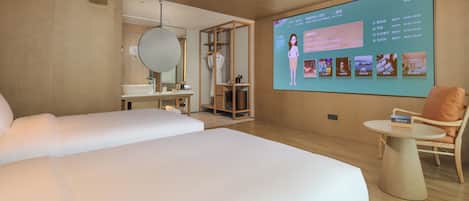 Habitación de hotel con dos camas, un espejo grande, una mesita pequeña y una pantalla proyectando información del hotel.