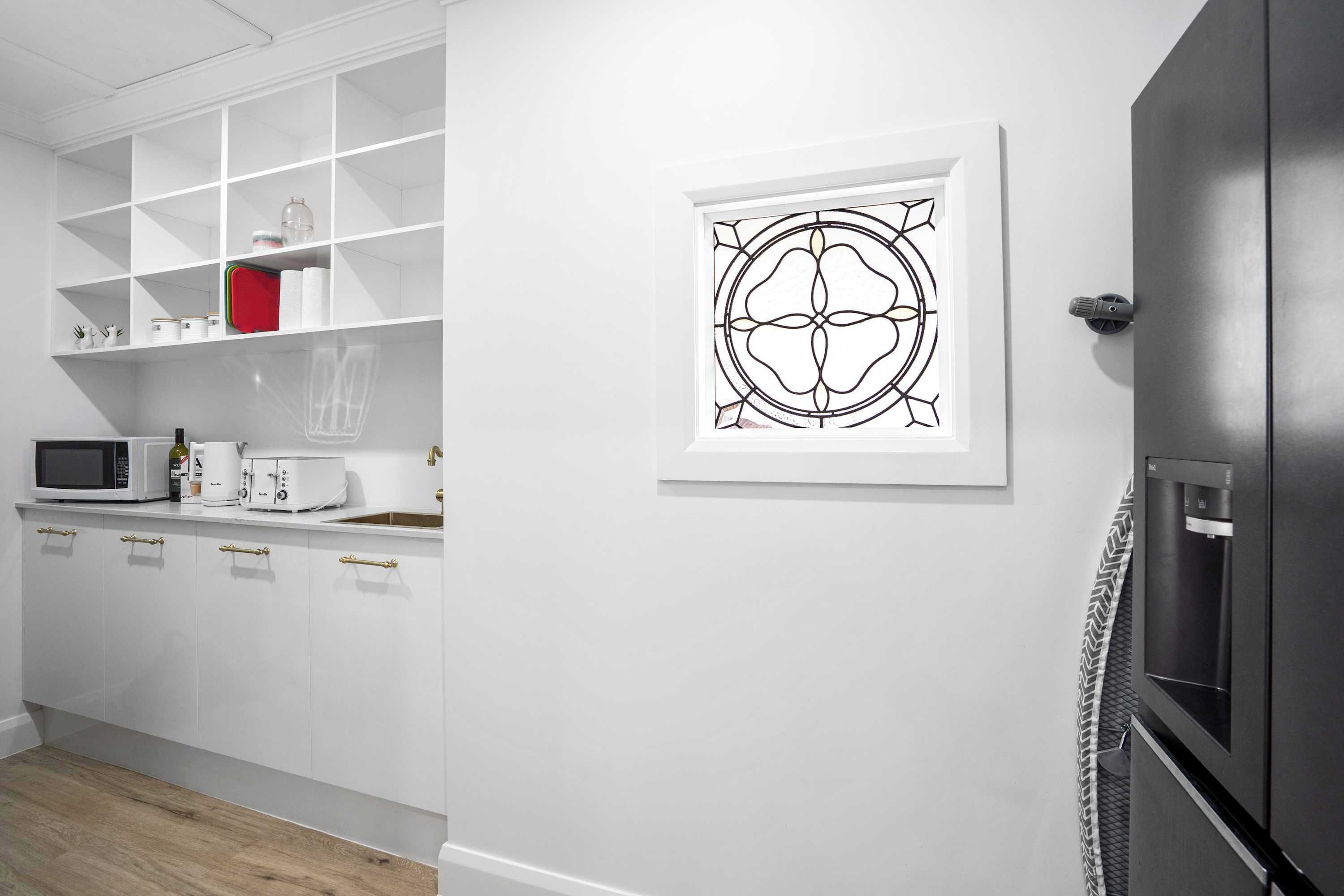 A modern kitchen with white cabinetry, a microwave, a toaster, and a refrigerator.