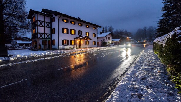 A two-story building with a snow-covered ground, a paved road in front, and a clear sky. - Grünstein Vacation Rental (Schönau am Königssee)