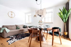 A modern living room with a round dining table, a sofa, and a large plant. - Grünstein Vacation Rental (Schönau am Königssee)