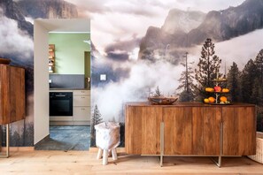 Eine Küche mit einem Holzkabinett, einem Herd und einem Essbereich mit einem Holztisch und einer dekorativen Obstauslage.