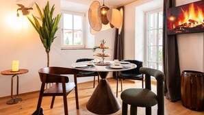 A dining area with a round table, chairs, a hanging light fixture, a plant, and a fireplace. - Grünstein Vacation Rental (Schönau am Königssee)