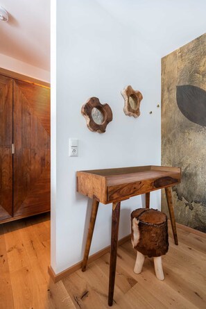 A wooden table with a unique design, a rustic stool, and two wooden wall art pieces. - Grünstein Vacation Rental, 53 square meters (Schönau am Königssee)