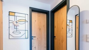 A hallway with wooden doors, a tiled floor, and a wall-mounted mirror. - Grünstein Vacation Rental (Schönau am Königssee)