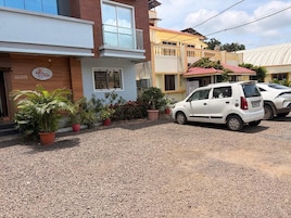 A building with a gravel driveway, potted plants, and parked cars.