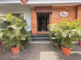 A building entrance with a wooden facade, a signboard, and potted plants.