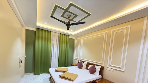 A hotel room with a bed, bedside tables, a ceiling fan, and a green curtain.