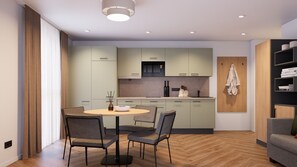 A modern kitchen with light green cabinets, a round dining table with chairs, and a wooden floor. - Apartment 3 North East - no balcony (Bad Reichenhall)