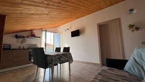 A dining area with a table and chairs, a kitchen in the background, and a door leading to another room. - Casa Genisi - Vacations in Scicli (Genovese)