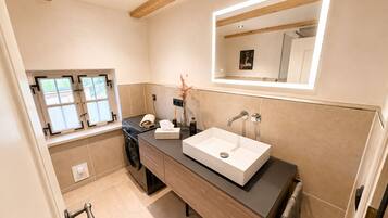 Ein modernes Badezimmer mit großem Fenster, integriertem Waschbecken und Spiegel darüber.