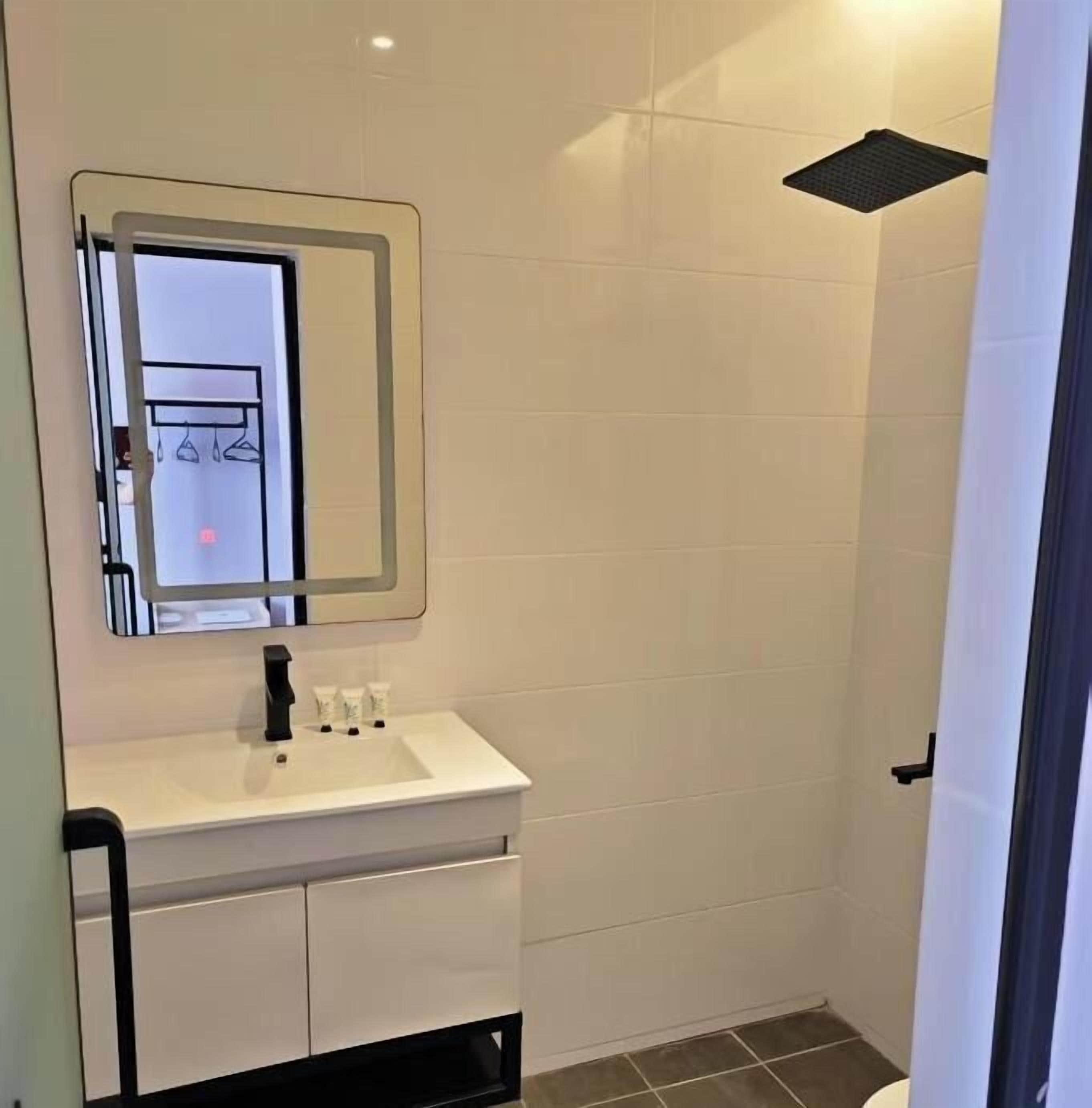 A modern bathroom with a white sink, mirror, and shower.