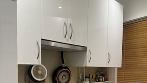 Een moderne keuken met witte kasten, een zwarte inductiekookplaat, een roestvrijstalen spoelbak en een inbouwoven.