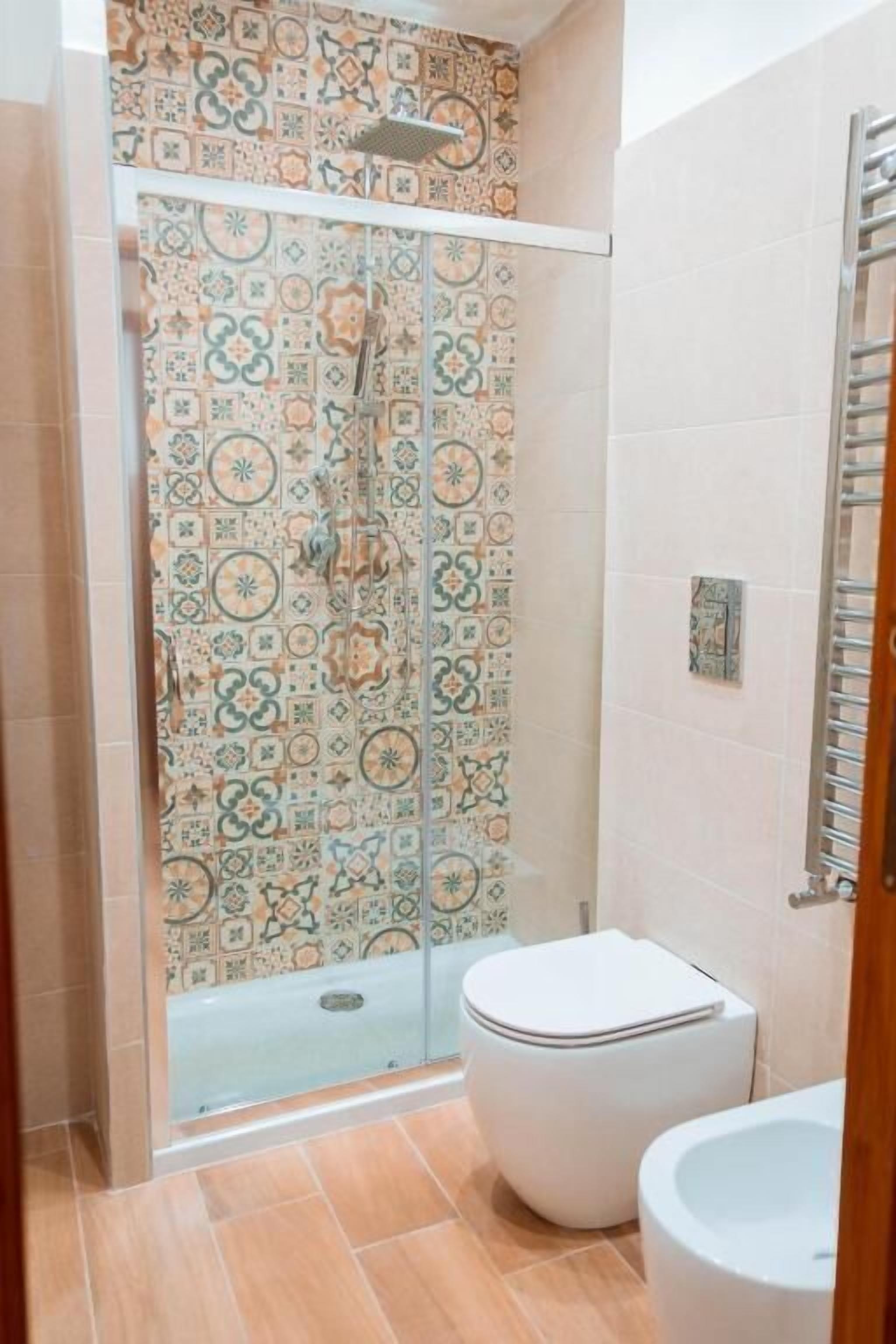 A bathroom with a shower enclosure, a toilet, and a sink.