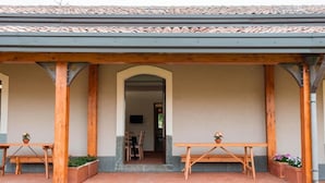 A covered outdoor seating area with wooden tables and chairs, a tiled roof, and a pathway leading to an interior space. - Terre di Monacella (Santa Venerina)