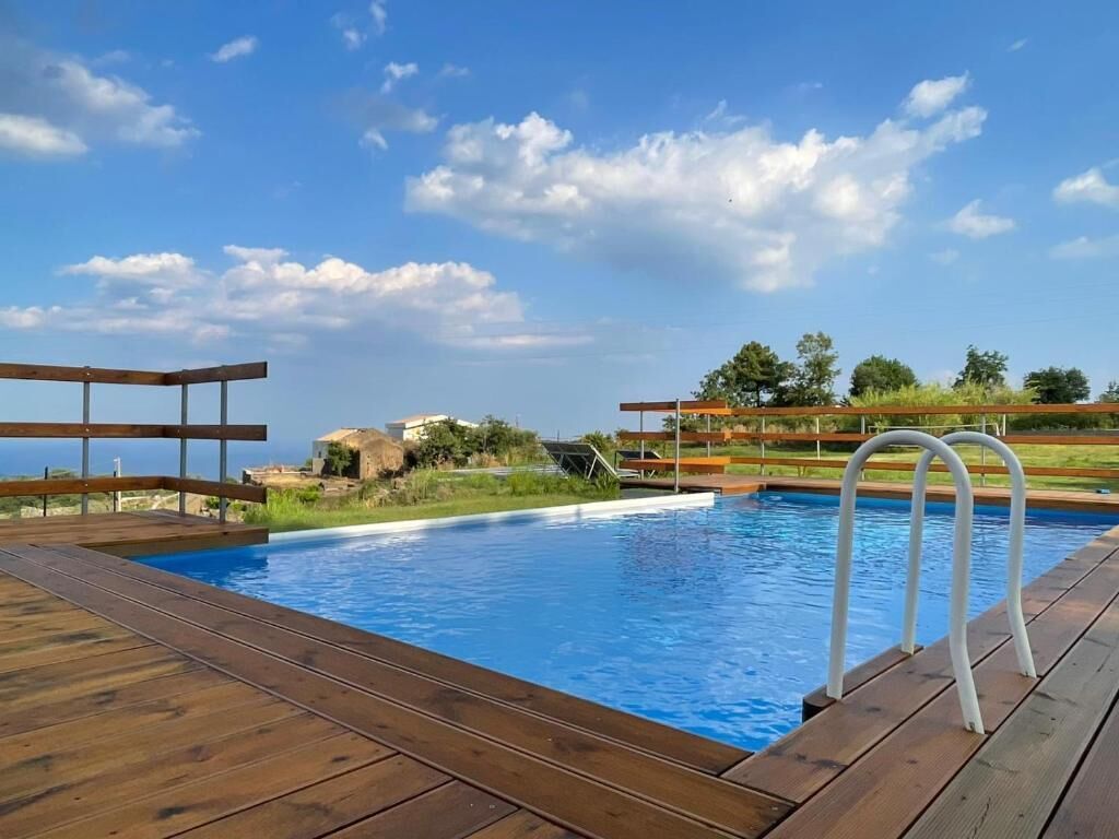 Een houten terras met een zwembad, een houten omheining en een heldere lucht.