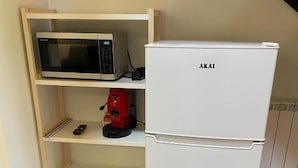 A compact kitchenette with a white refrigerator, a microwave, and a red coffee maker on a shelf. - Terre di Monacella (Santa Venerina)