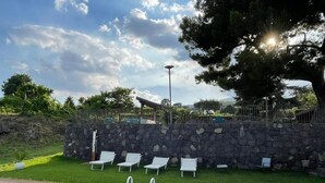 A swimming pool with a wooden deck, surrounded by a stone wall and white lounge chairs. - Terre di Monacella (Santa Venerina)