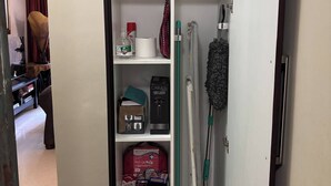 Ein Hotelzimmer mit einem Schrank, der Handtücher, einen Erste-Hilfe-Kasten, Reinigungsmittel und einen Staubsauger beinhaltet.