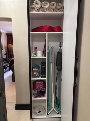 Ein Hotelzimmer mit einem Schrank, der Handtücher, einen Erste-Hilfe-Kasten, Reinigungsmittel und einen Staubsauger beinhaltet.