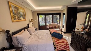 Ein Hotelzimmer mit einem großen Bett, einer Sitzecke mit einer Couch, einem Schreibtisch und einem Kleiderschrank.