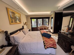 Ein Hotelzimmer mit einem großen Bett, einer Sitzecke mit einer Couch, einem Schreibtisch und einem Kleiderschrank.