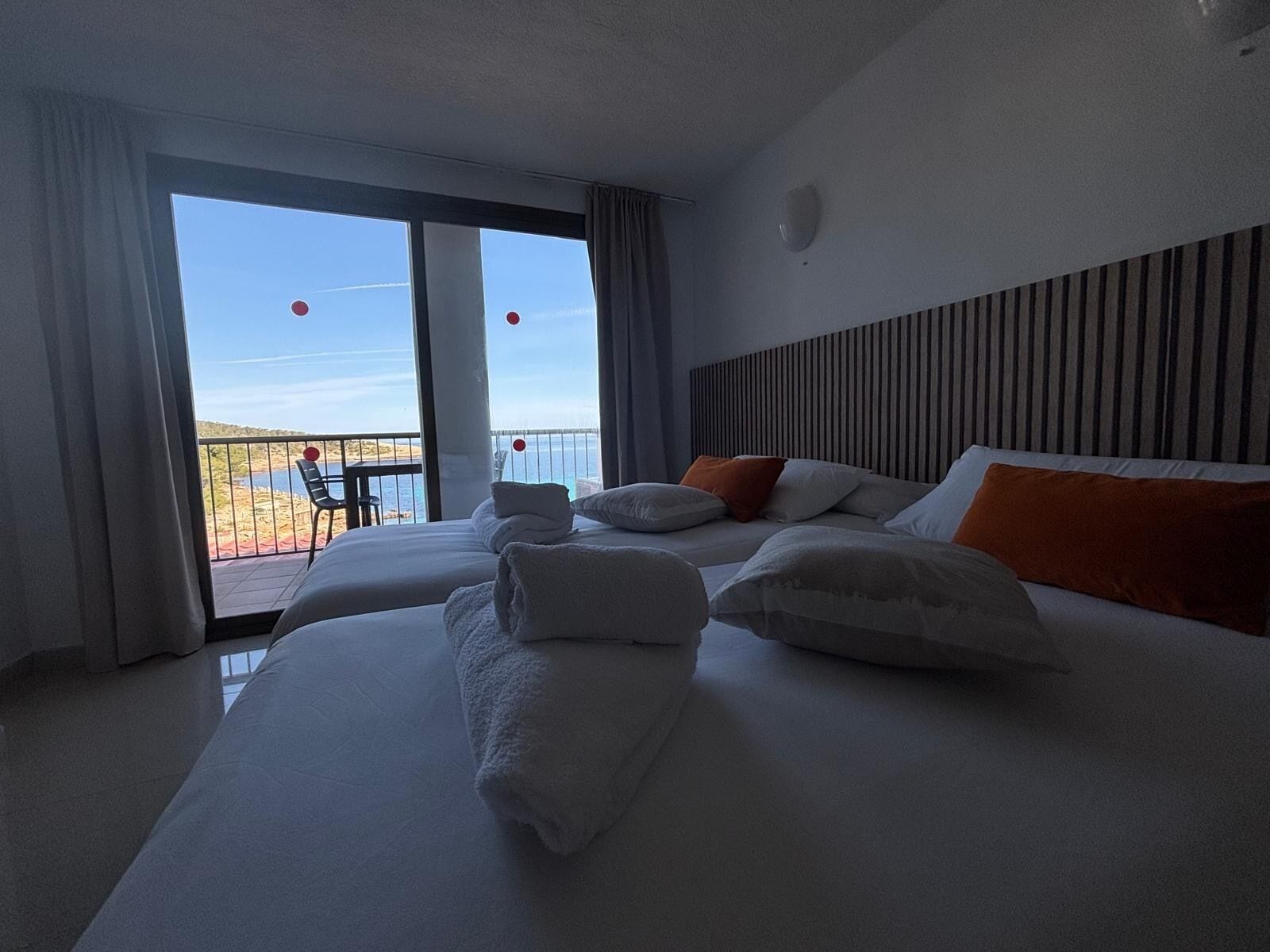 A hotel room with a large bed, a view of the sea, and a balcony.