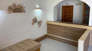 A reception area with a wooden reception desk, a cushioned bench, and decorative wall art. - Es Grop Apartments (IB)