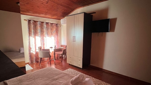 Un dormitorio con cama, escritorio, silla, armario y televisor.