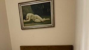 Habitación de hotel con cama, un cuadro en la pared y una mesita de noche con un control remoto.