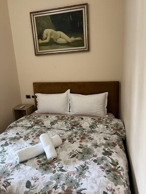 Habitación de hotel con cama, un cuadro en la pared y una mesita de noche con un control remoto.