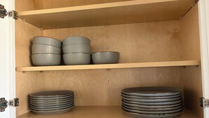 Un meuble avec deux étagères : l’une pour ranger des bols empilés et l’autre pour ranger des assiettes empilées.