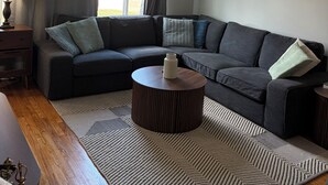 A modern living room with a sectional sofa, a round coffee table, and a patterned rug.