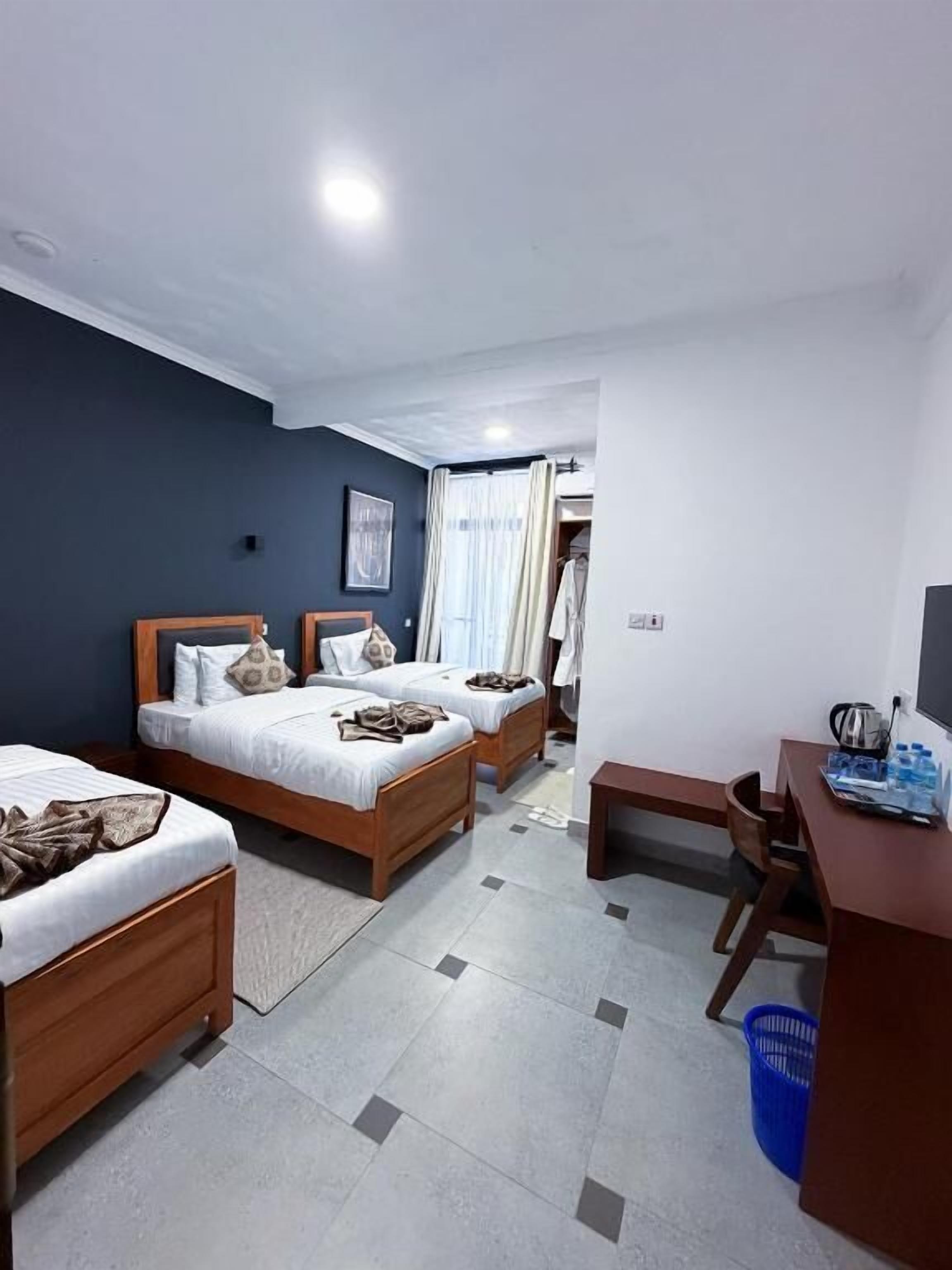 A hotel room with two beds, a desk, and a chair.