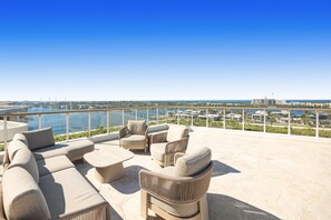 A rooftop terrace with outdoor seating and a view of the city and water. - Poolside 2-bed Apartment at Lake Kawana (Sunshine Coast)