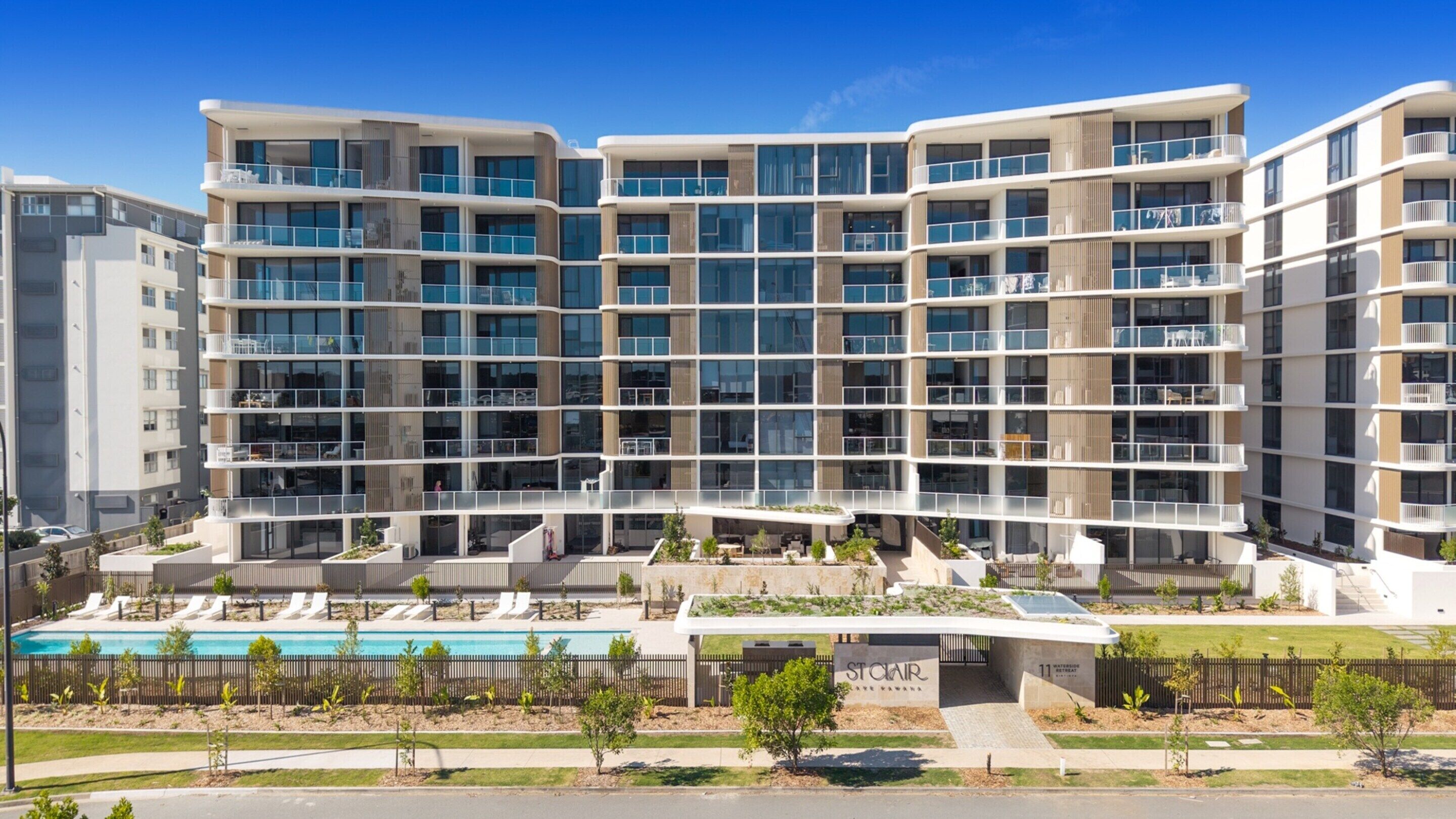 A multi-story residential building with balconies, a swimming pool, and a landscaped area.