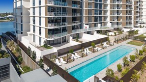 A multi-story residential building with a rooftop pool and outdoor seating area. - Poolside 2-bed Apartment at Lake Kawana (Sunshine Coast)