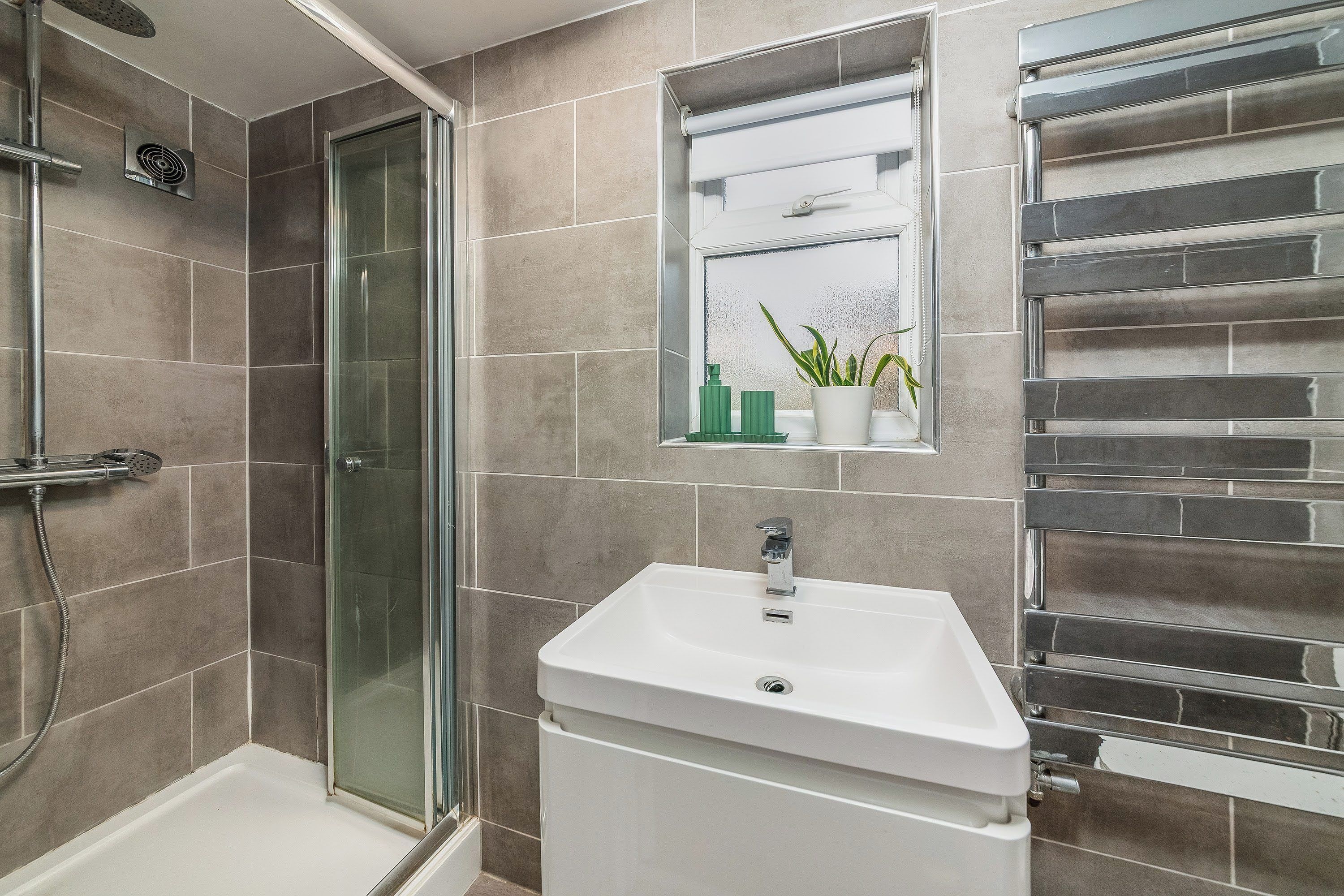Une salle de bain avec une douche à parois de verre, un lavabo blanc et un porte-serviettes.