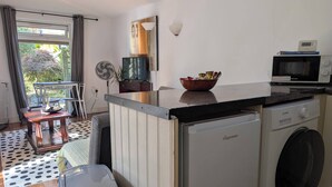 Eine kleine Küche mit Waschmaschine, Mikrowelle und Essbereich mit Tisch und Stühlen.