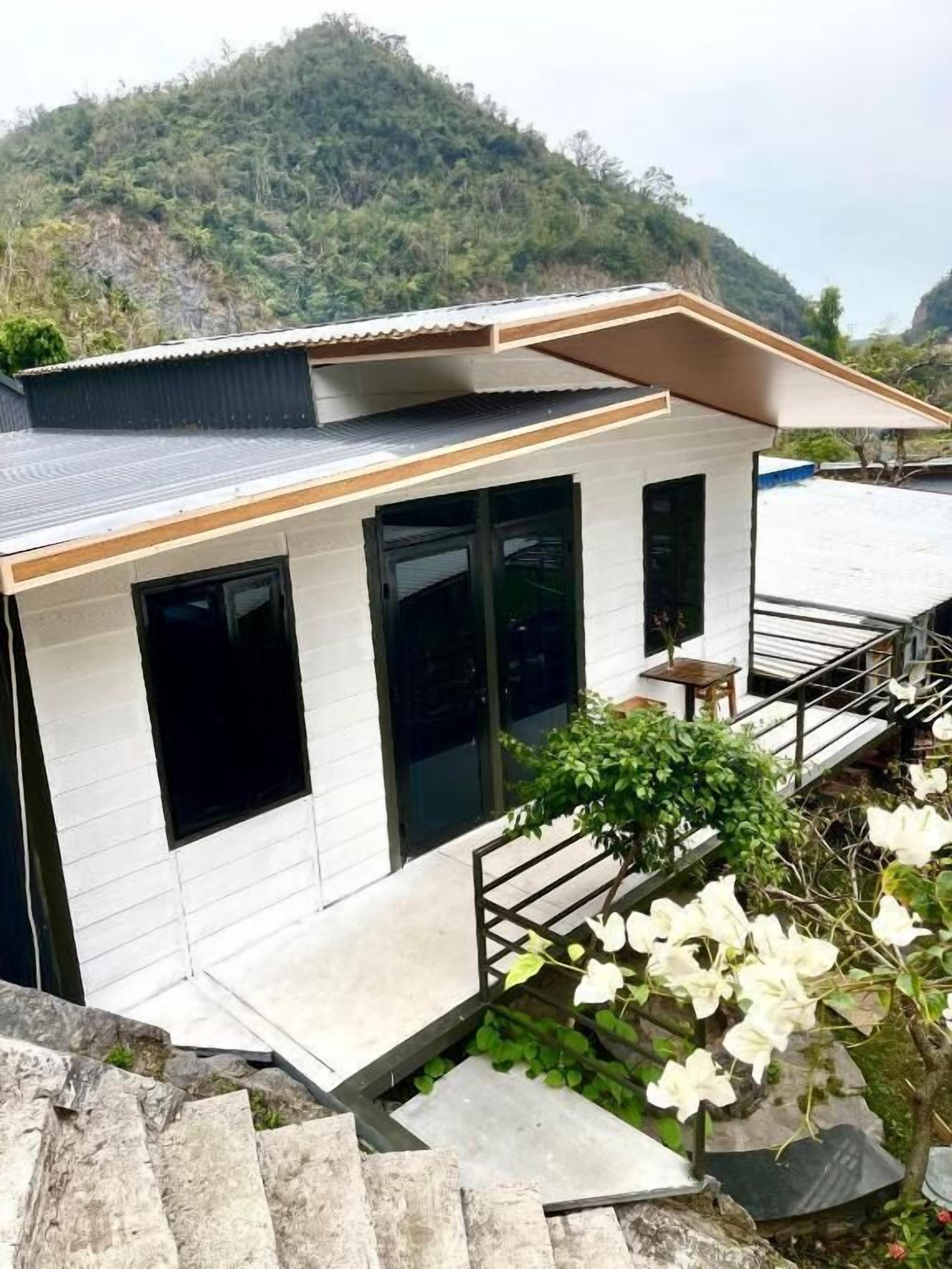 Uma casa moderna com telhado plano, janelas amplas e uma escadaria que leva a um deck.