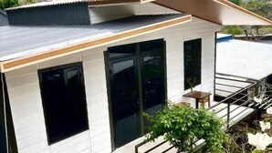 A modern house with a flat roof, large windows, and a staircase leading to a deck. - Cat Ba Love House (Hai Phong)