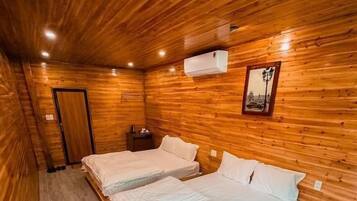 A wooden-paneled room with two beds, a nightstand, and a framed picture on the wall.