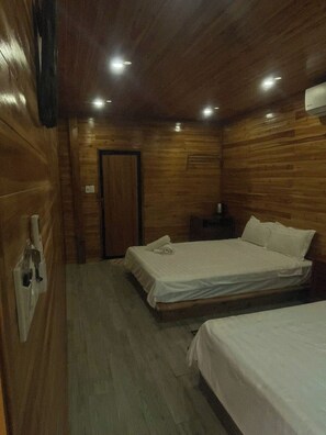 Una habitación con paredes de madera y una cama con ropa blanca.