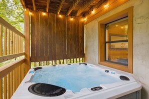 A hot tub with a wooden deck and a window. - Bear Run Getaway | Near Downtown Gatlinburg (Gatlinburg)