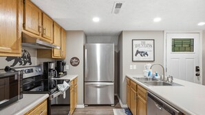 A modern kitchen with wooden cabinets, stainless steel appliances, and a double sink. - Bear Run Getaway | Near Downtown Gatlinburg (Gatlinburg)