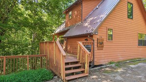 A wooden cabin with a porch, a staircase, and a sign indicating it's a Bear Run Getaway. - Bear Run Getaway | Near Downtown Gatlinburg (Gatlinburg)