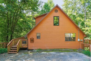 A wooden cabin with a wooden staircase leading to the entrance, a small window, and a sign indicating it is a Bear Run Getaway. - Bear Run Getaway | Near Downtown Gatlinburg (Gatlinburg)